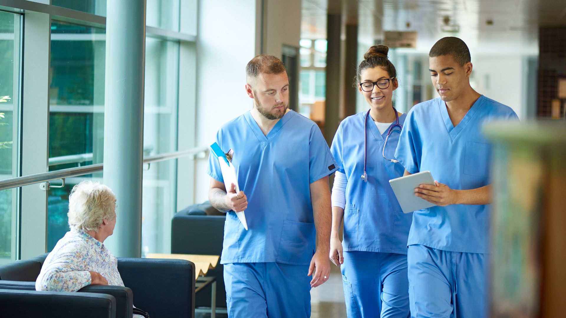 Nurses assist a patient as they walk together down a hospital hallway, promoting care and support in a healthcare setting.